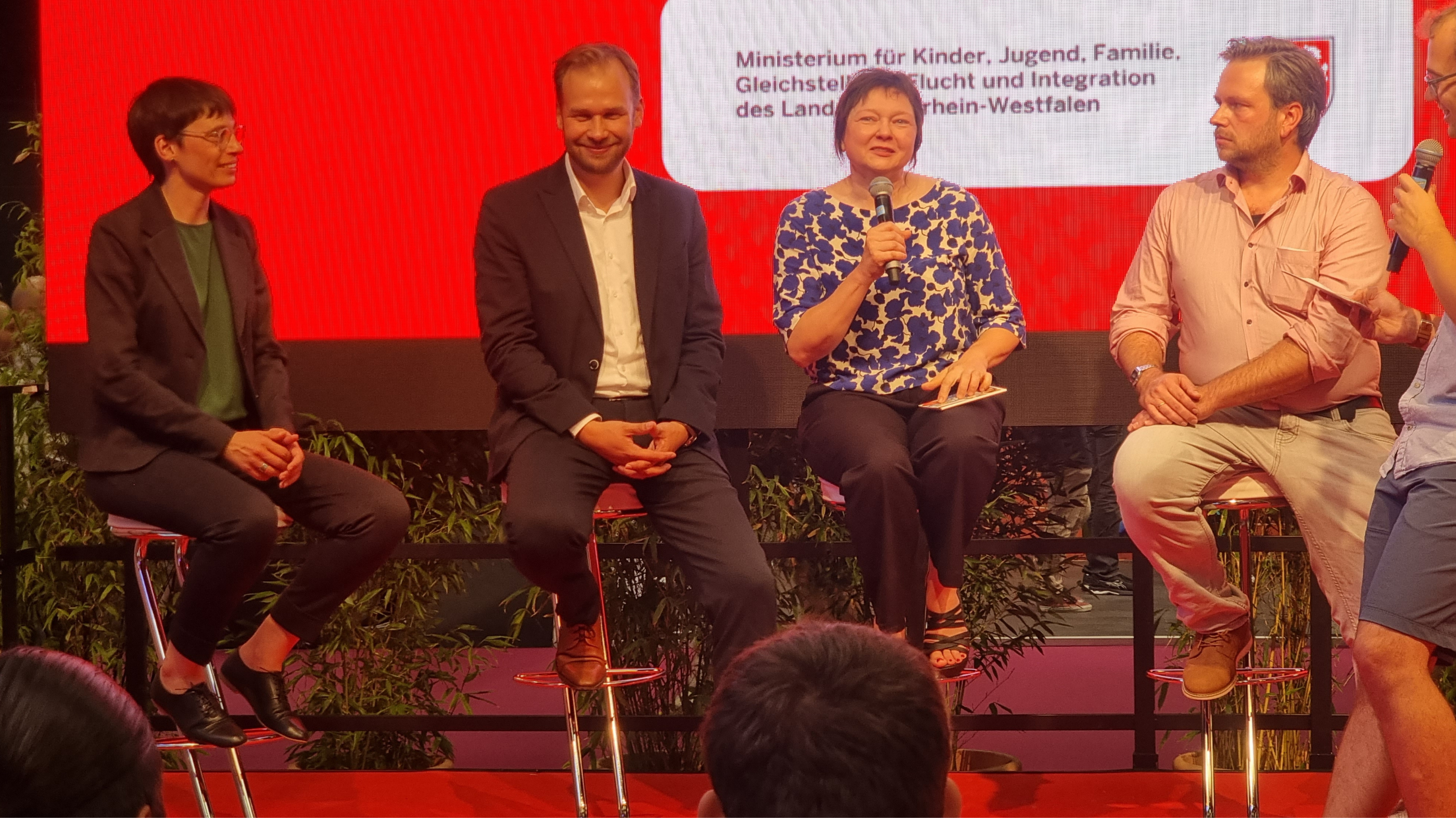 v.l.n.r.: Ministerin Josefine Paul, Robert Voigtsberger, Beigeordneter für Bildung, Jugend und Sport der Stadt Köln, Dr. Christine Ketzer von der LAG LM und Markus Sindermann von der FJMK auf der Bühne des Jugendforums NRW 2022